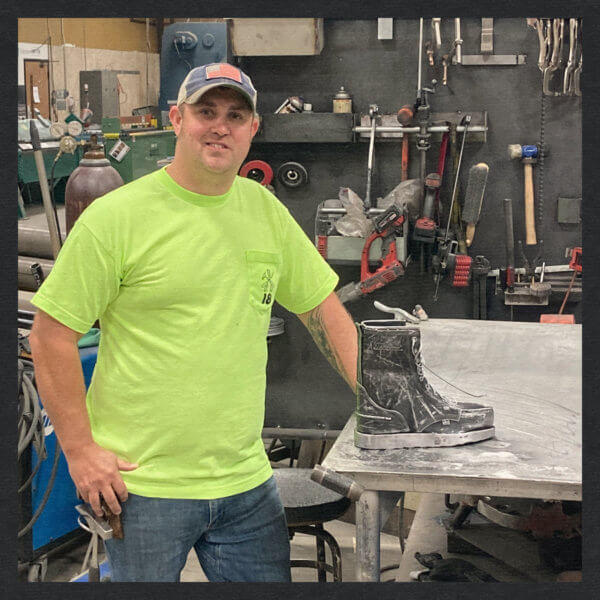Image of a guy standing next to a boot he made out of metal
