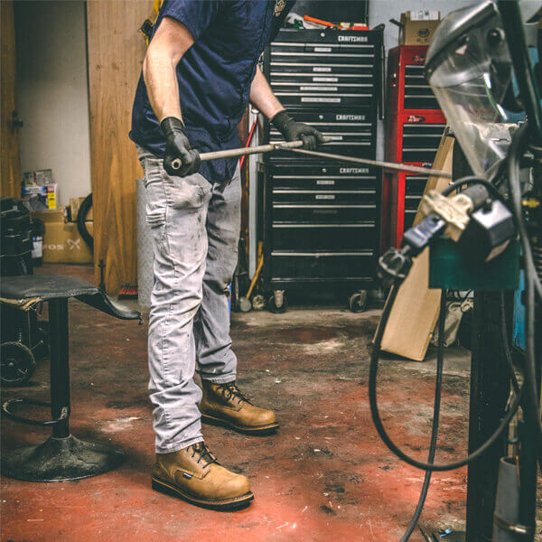 Image of a person using a tool in a workshop wearing the V-series waterproof/insulated 8"