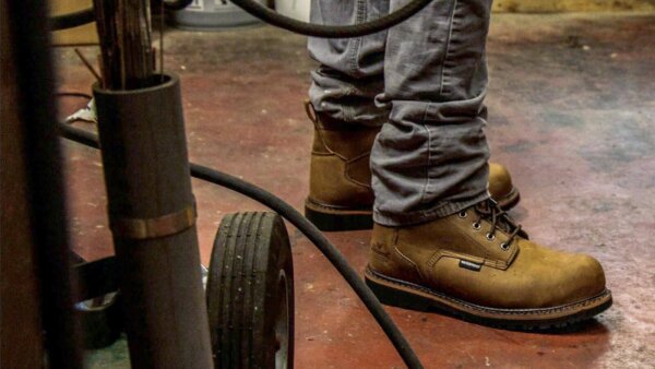 Man wears waterproof work boots to hose down floor.