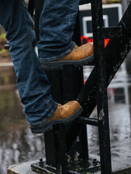 Genesis safety toe work boots double as rain boots, helping this worker climb a ladder in wet weather.