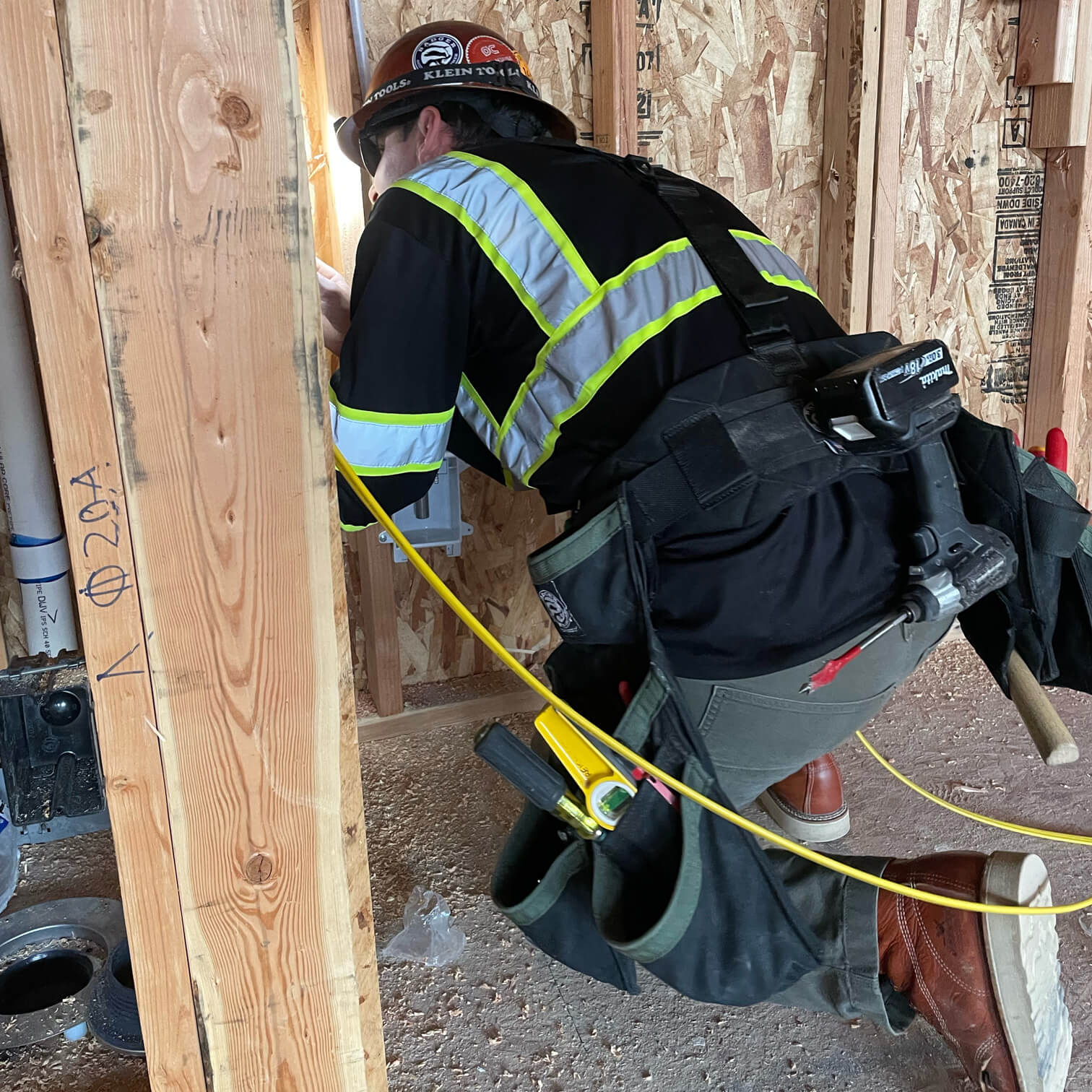 Image of a guy kneeling on the ground doing electrical work