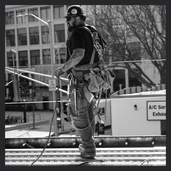 Image of a iron worker with all his safety gear on looking off in the distance